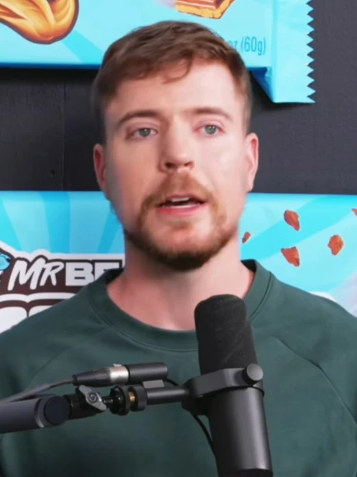 MrBeast parla al microfono in un’intervista del 2025, con prodotti Feastables sullo sfondo