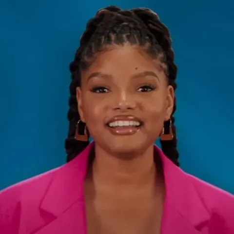 Halle Bailey sorridente con una giacca rosa durante la promozione di The Little Mermaid nel 2023